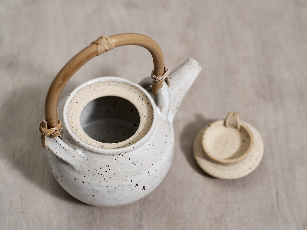 A Tea Pot – Speckled with Bamboo handle by Nicola Shuttleworth on a wooden table.