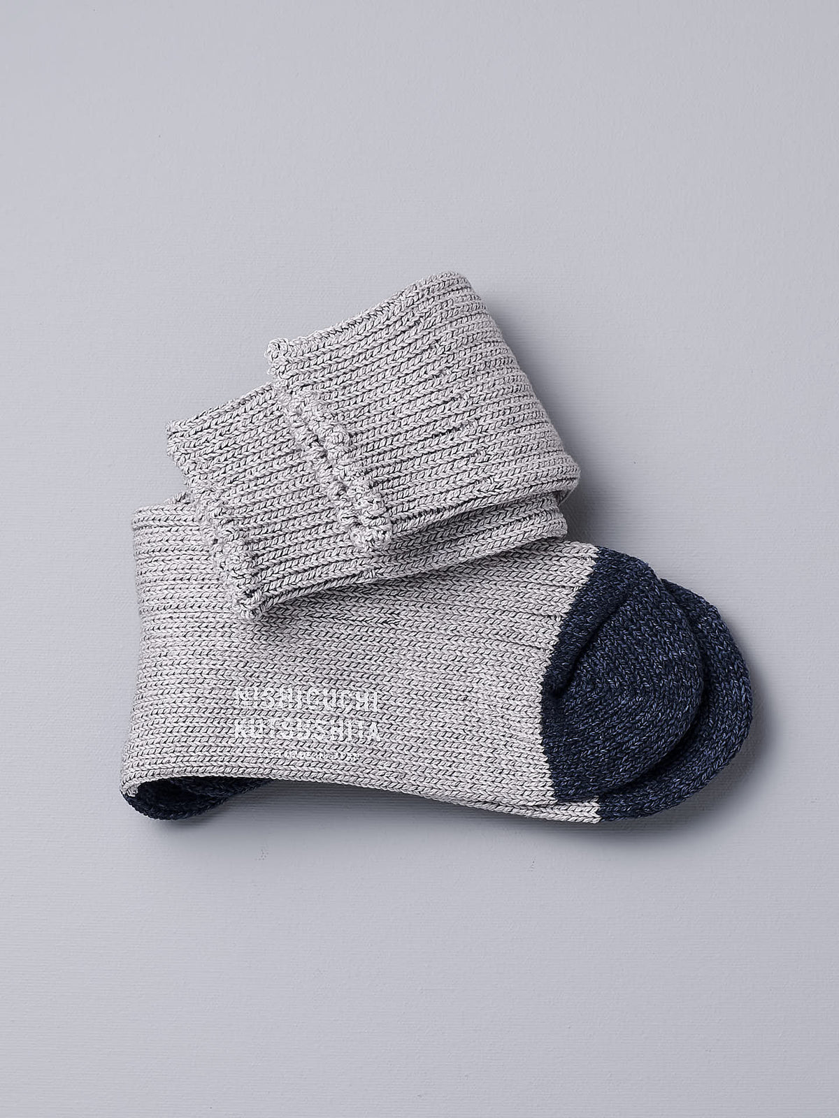 A pair of Boston Slab Socks - Grey Denim by Nishiguchi Kutsushita on a white background.