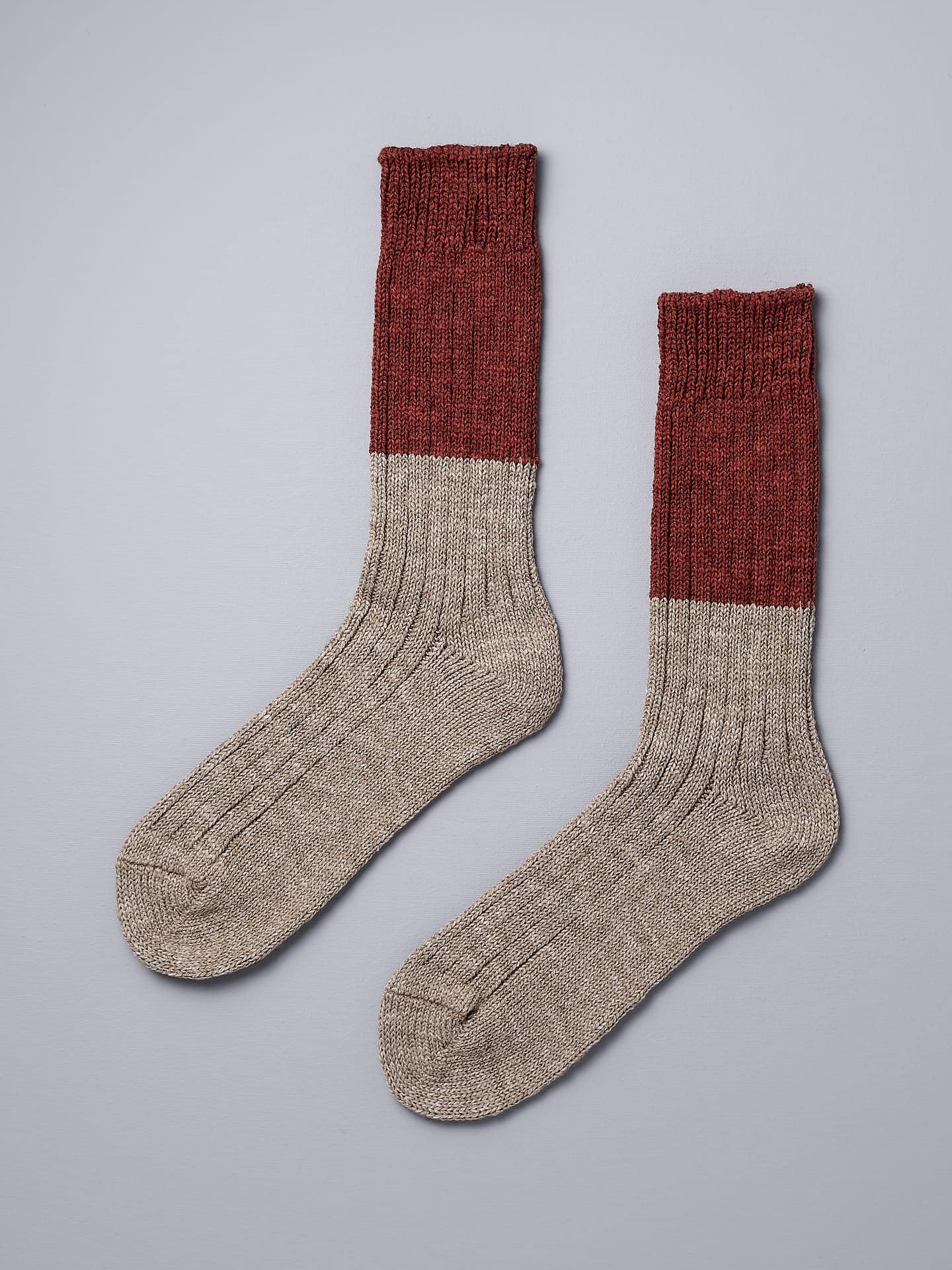 A pair of Boston Slab Socks – Red Brick by Nishiguchi Kutsushita on a grey background.