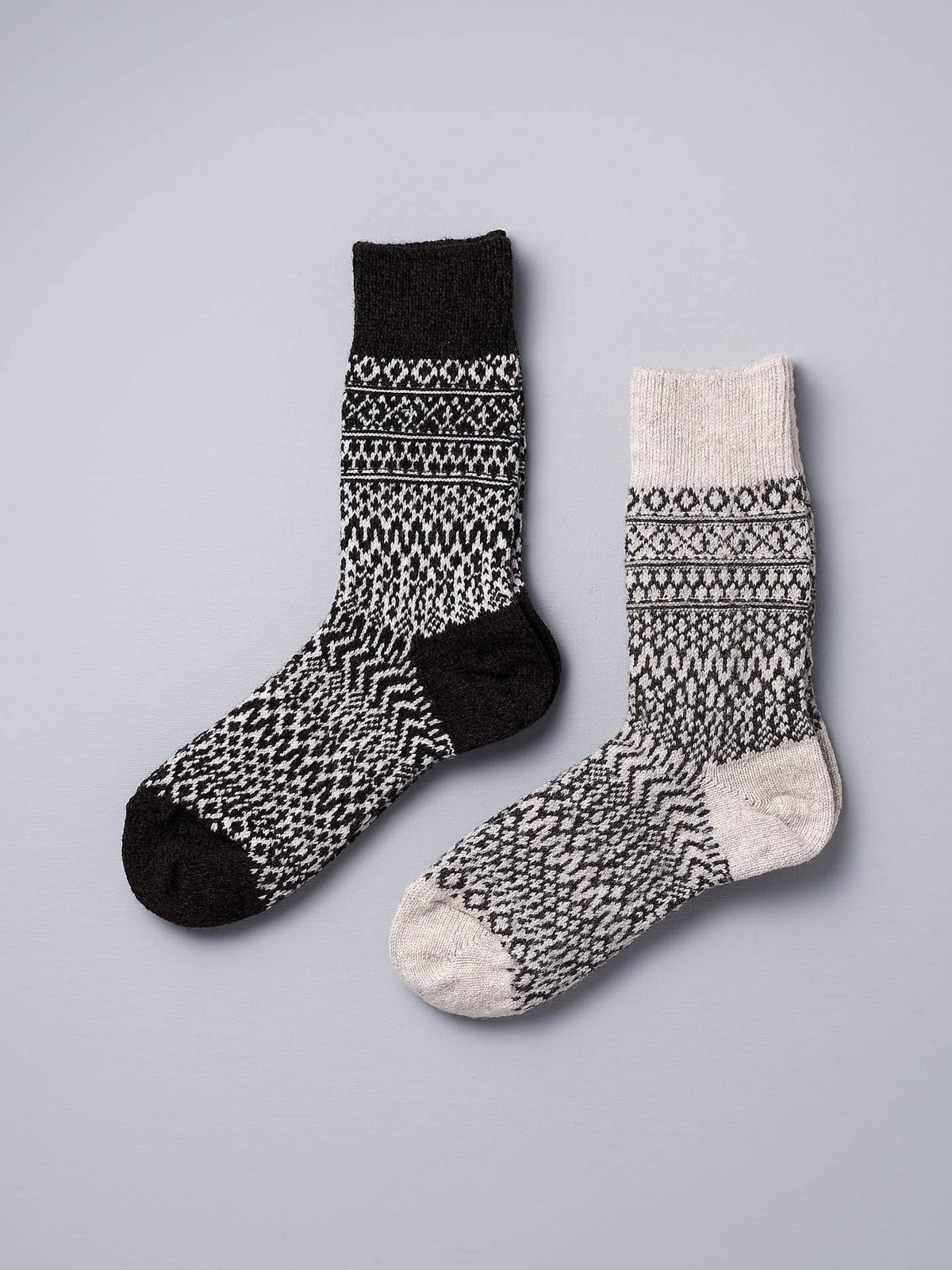 A pair of Oslo Wool Jacquard Socks - Coffee by Nishiguchi Kutsushita on a grey background.