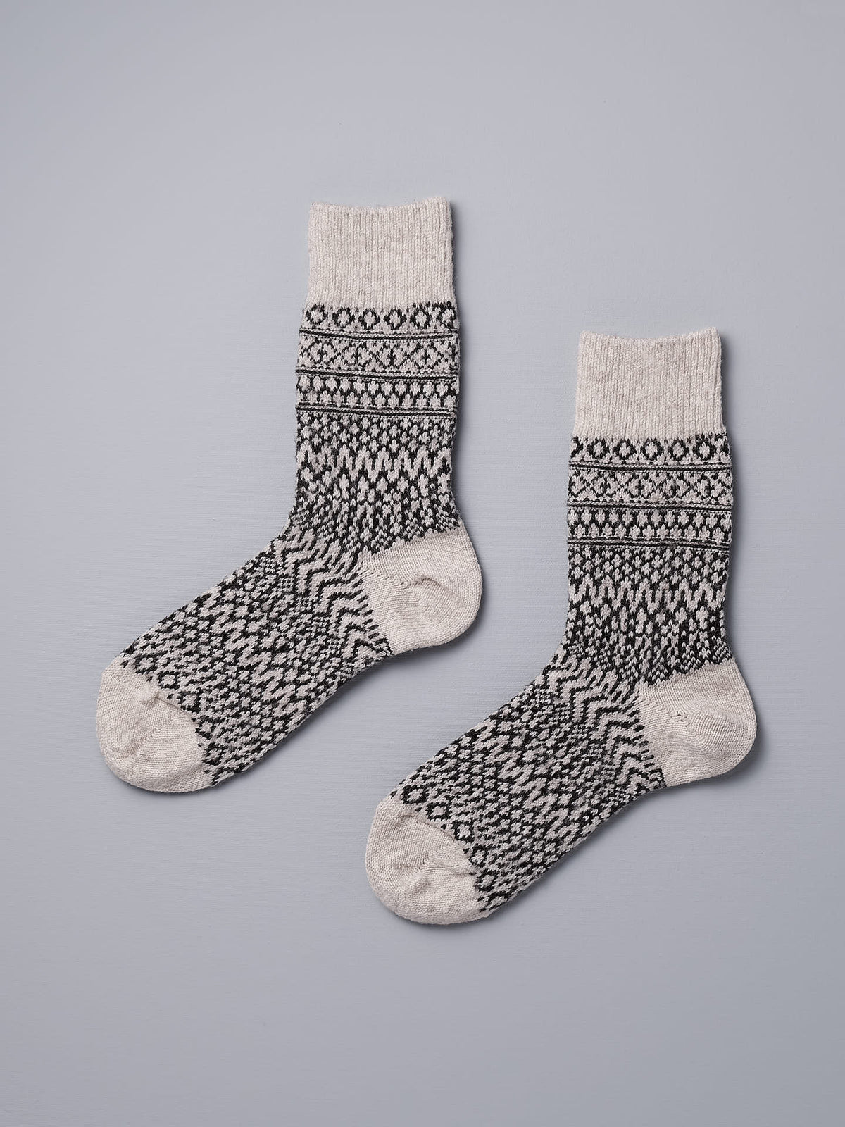 A pair of Oslo Wool Jacquard Socks – Oatmeal by Nishiguchi Kutsushita on a grey background.