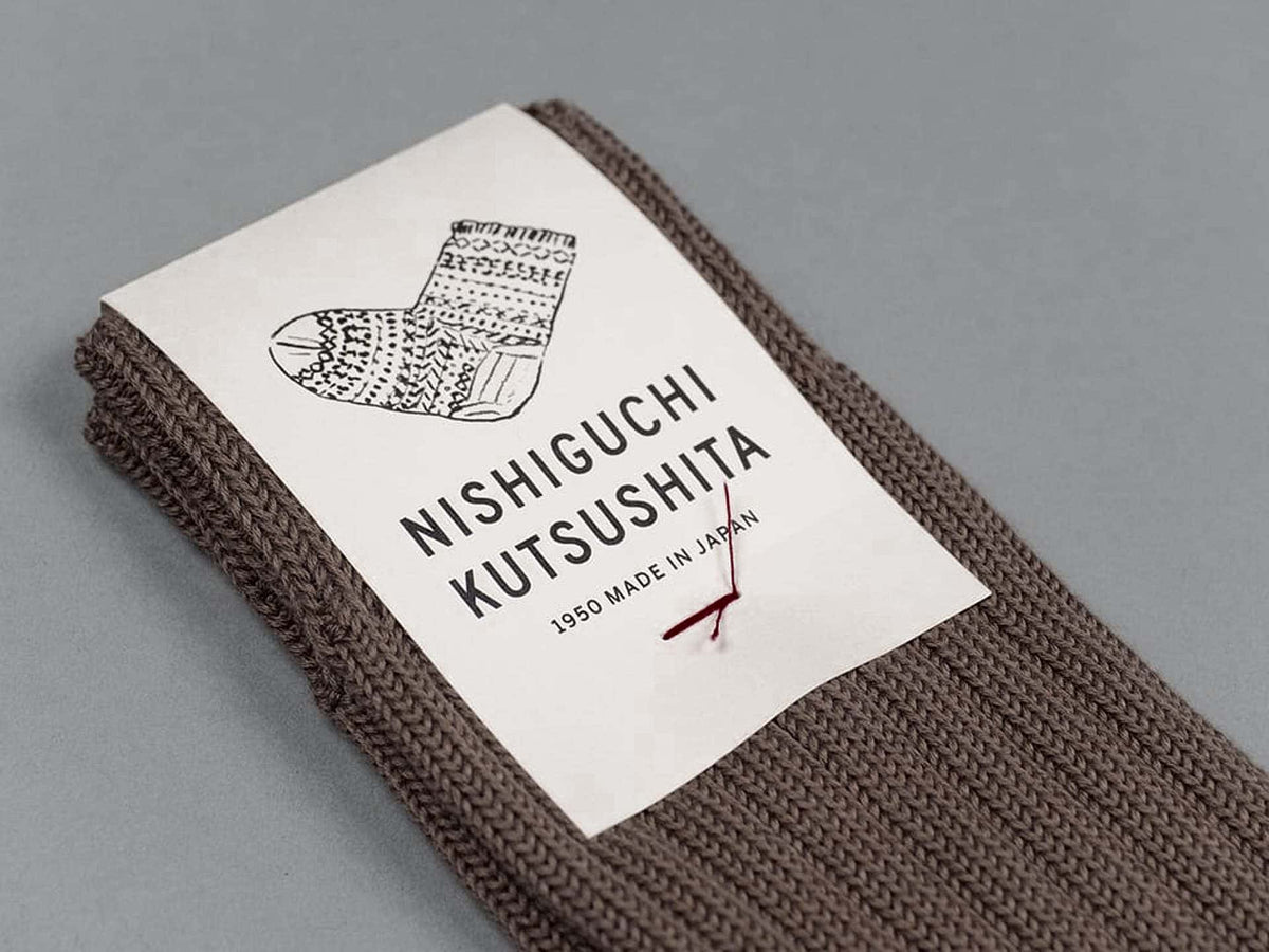 A pair of Praha Cotton Socks – Chocolate Milk with a label that says Nishiguchi Kutsushita.