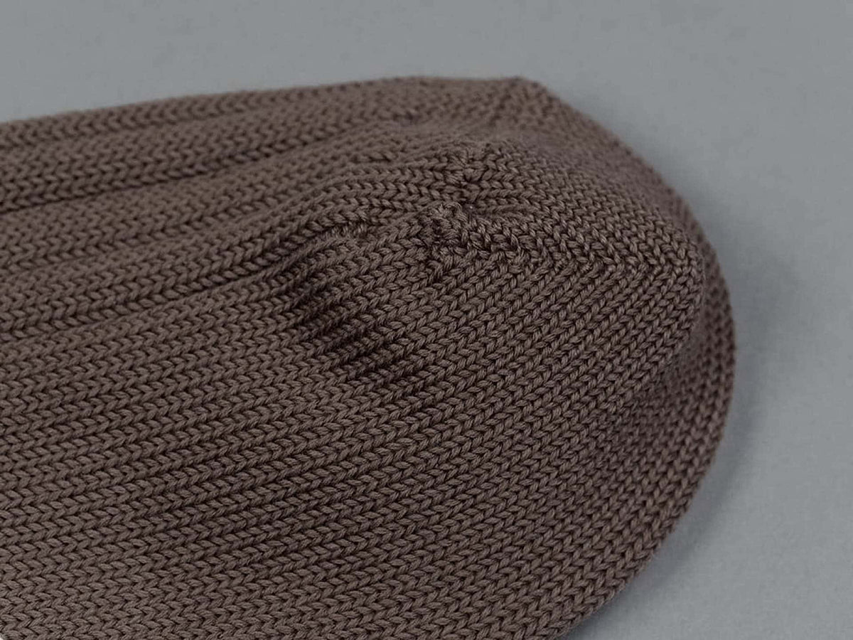 A Praha Cotton Socks – Chocolate Milk by Nishiguchi Kutsushita on a grey surface.
