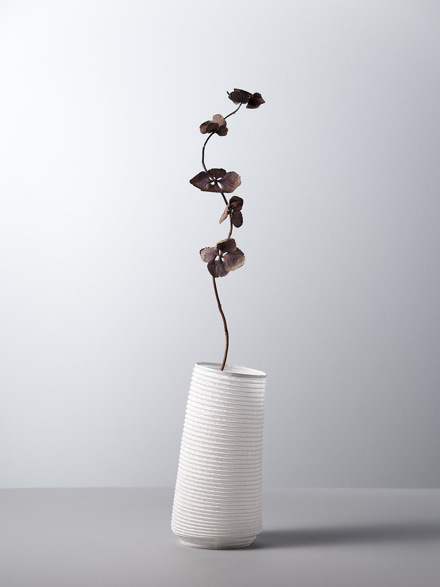 A Nobi-tsutsu Paper Vase - №3 by Hayashi Kougei with a flower in it.