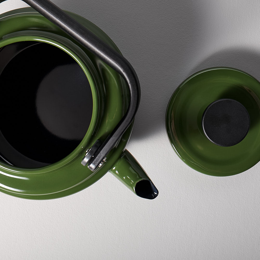An Amu Stove-top Kettle – Green and a black teapot on a grey surface. (Brand Name: Noda Horo)