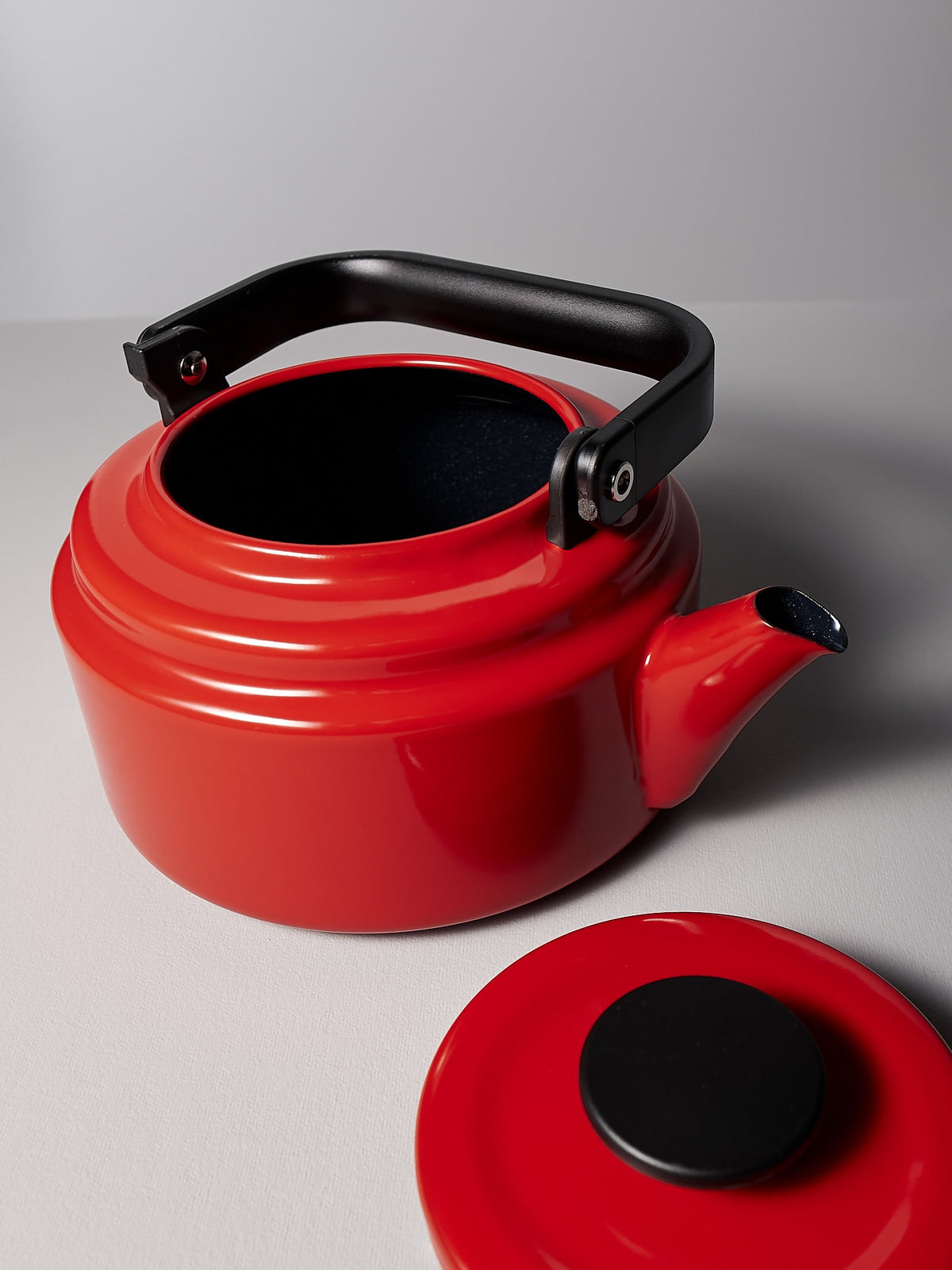 A Noda Horo Amu Stove-top Kettle - Red with a black handle.