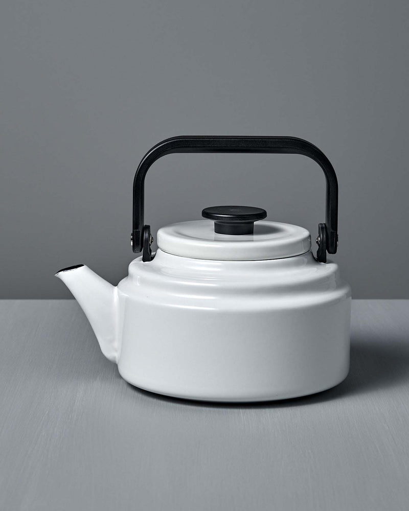 A white Amu Stove-top Kettle with a black handle on a grey background. (Brand: Noda Horo)