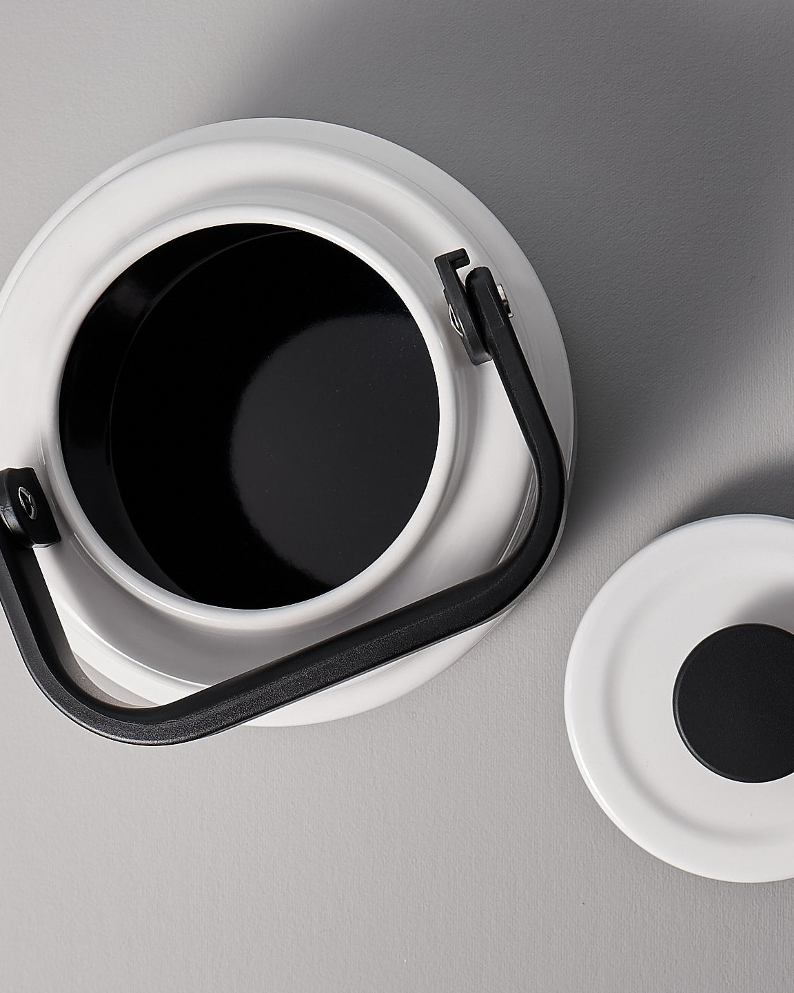 A white Amu Stove-top Kettle with a black handle on a grey background. (Brand: Noda Horo)