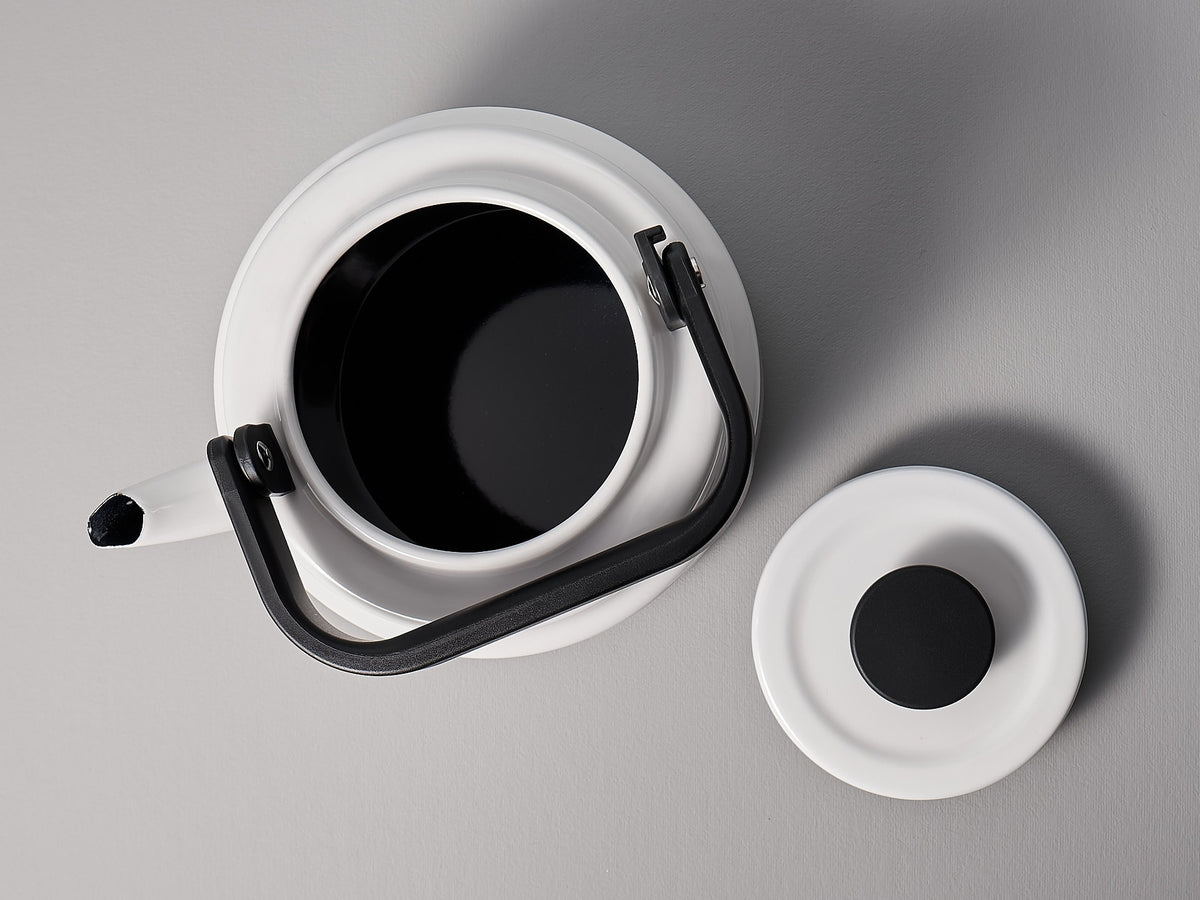 A black and white Amu Stove-top Kettle - White cup and saucer on a white surface, from the brand Noda Horo.