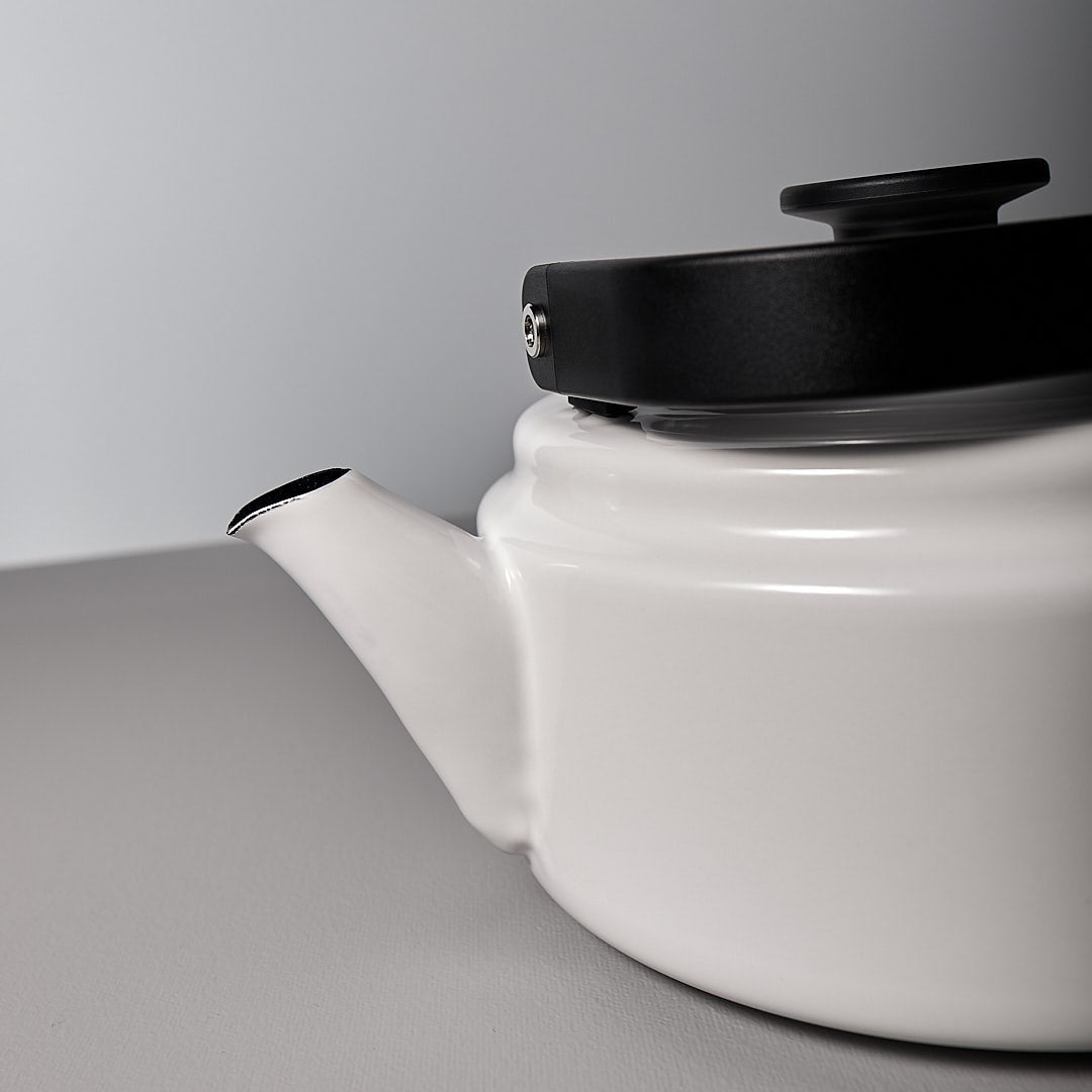 A Noda Horo Amu Stove-top Kettle - White with a black lid on a table.