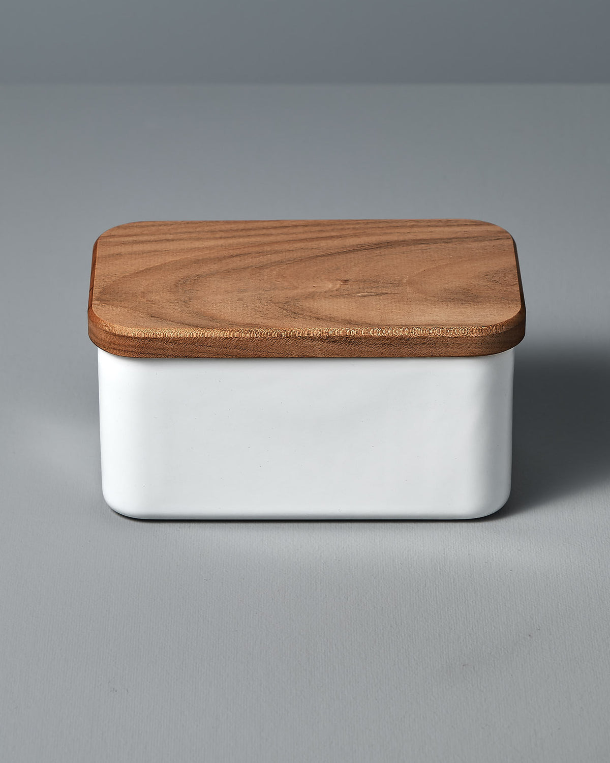 A Noda Horo Enamel Butter Case – 450𝚐 with a wooden lid on a grey surface.