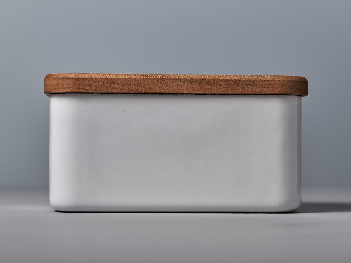 A Noda Horo Enamel Butter Case – 450𝚐 with a wooden lid on a grey background.