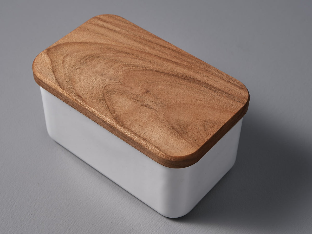 A Noda Horo Enamel Butter Case – 450𝚐 with a wooden lid on a grey surface.