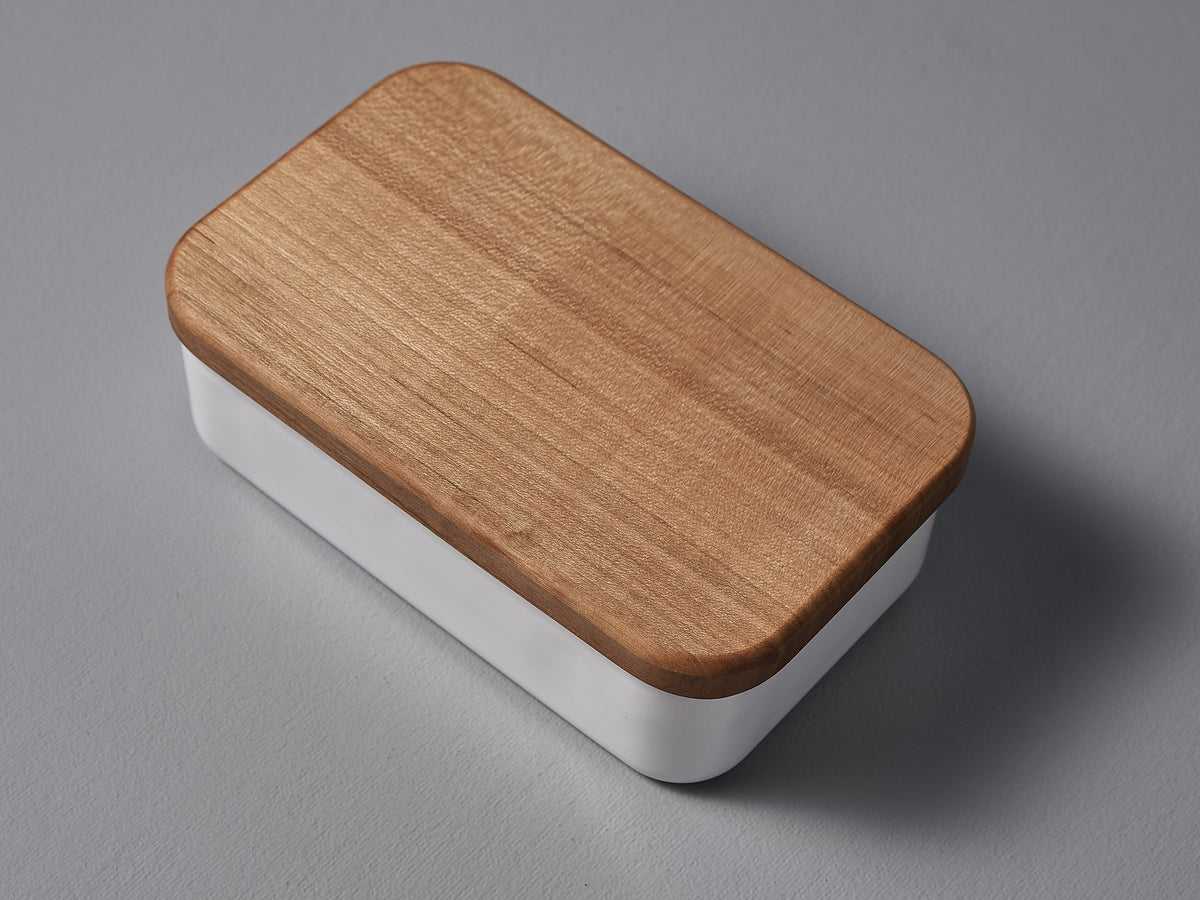 A Noda Horo Enamel Butter Case - 200g with a lid on a grey surface.