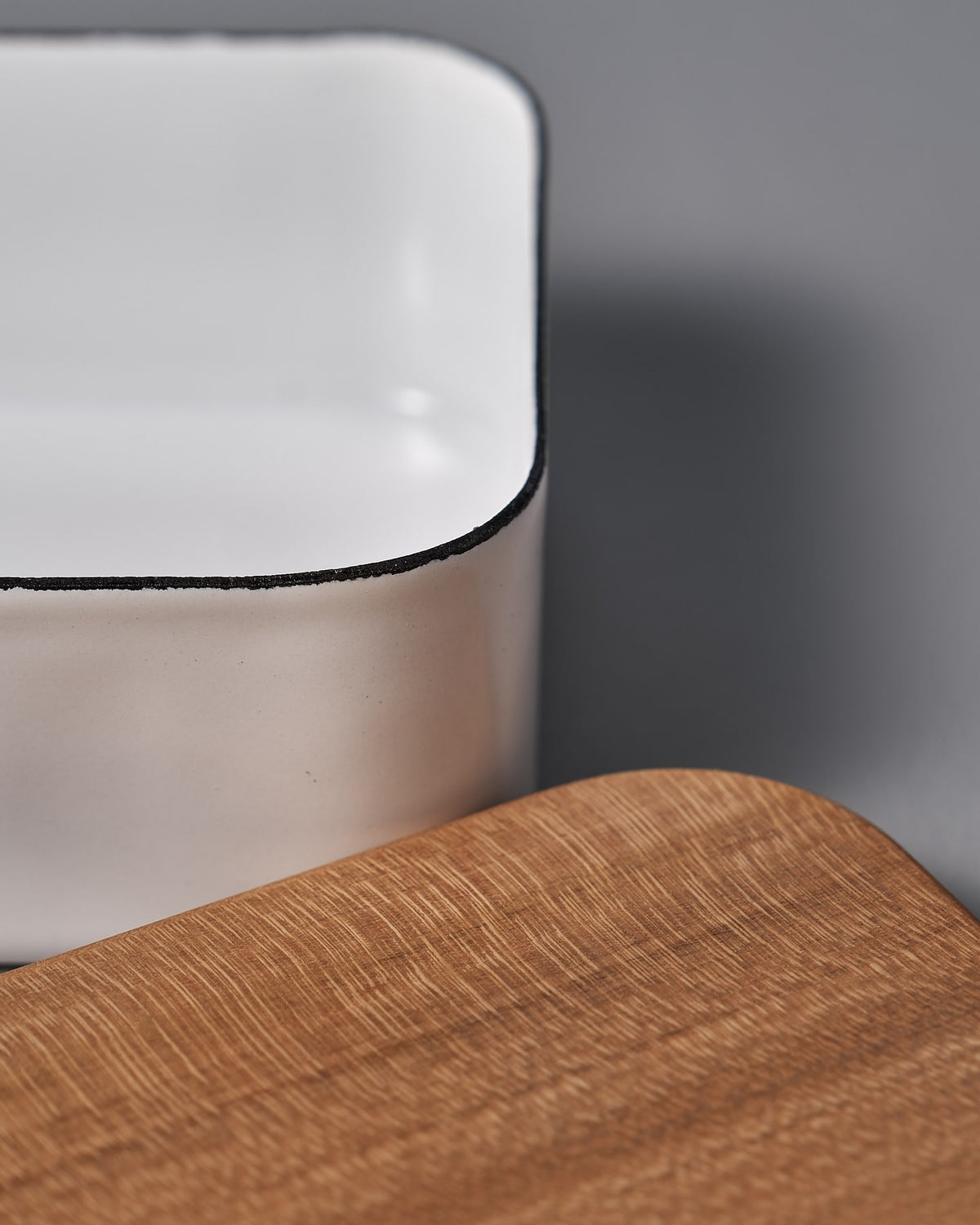 A Noda Horo Enamel Butter Case - 200𝚐 on a wooden cutting board.