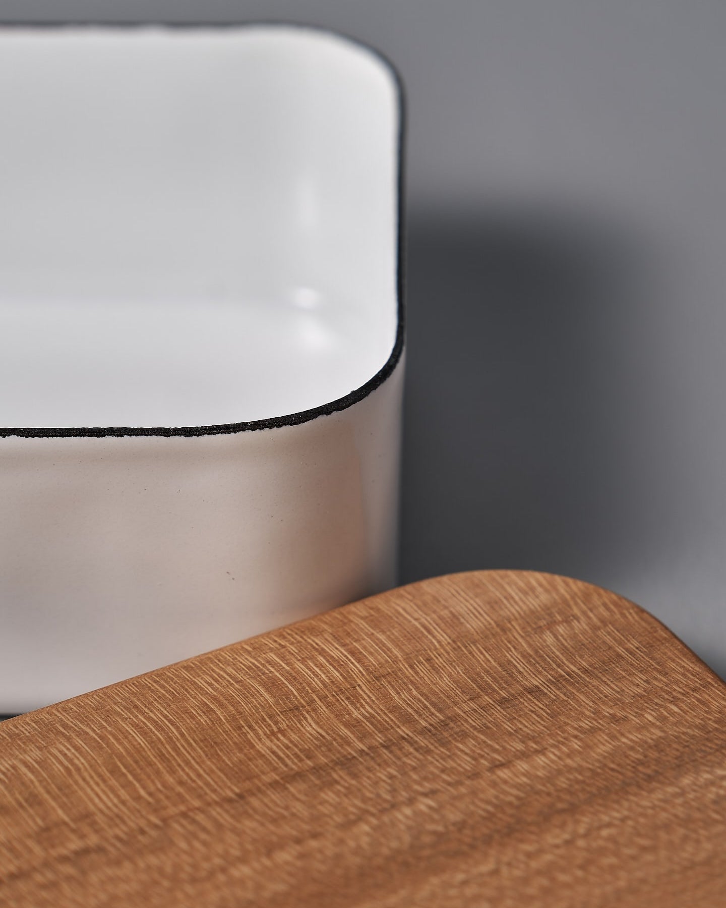 The Noda Horo Enamel Butter Case – 200g, with its sleek white ceramic body and cherry wood lid, rests elegantly on a gray surface, providing stylish food storage.