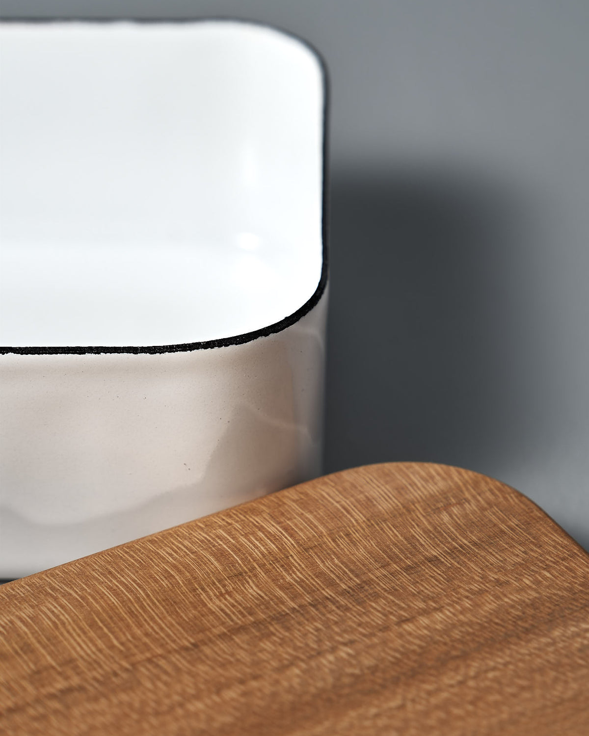 A white and black Enamel Butter Case – 450𝚐 by Noda Horo on top of a wooden cutting board.