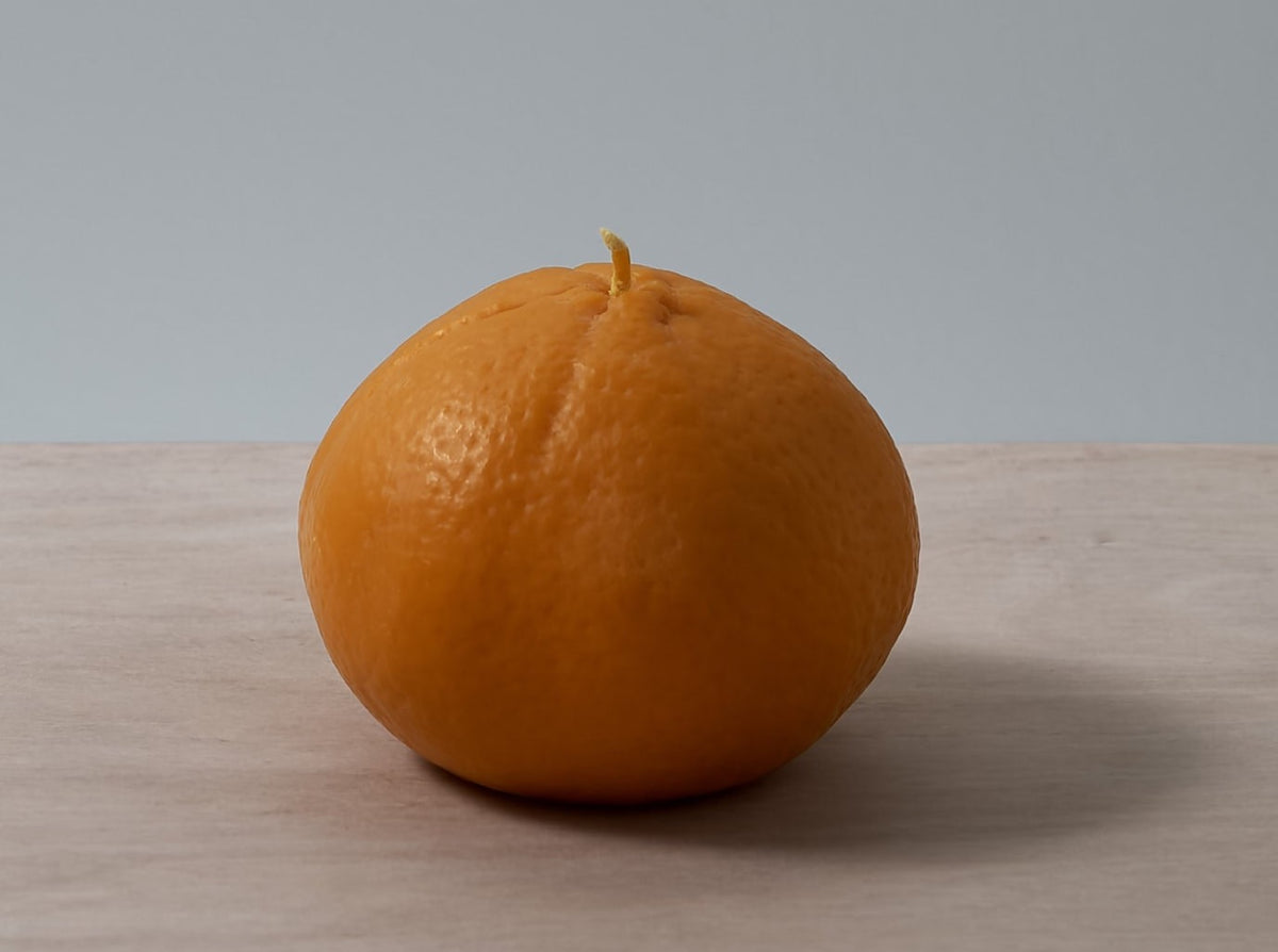 A Mandarin Candle – Large, made by Nonna&#39;s Grocer, sitting on a wooden table.