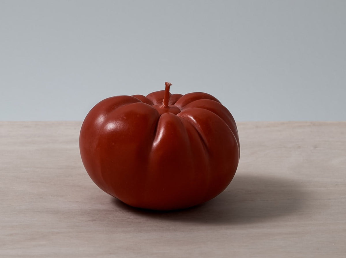 A Tomato Candle - Medium from Nonna&#39;s Grocer sitting on top of a wooden table.