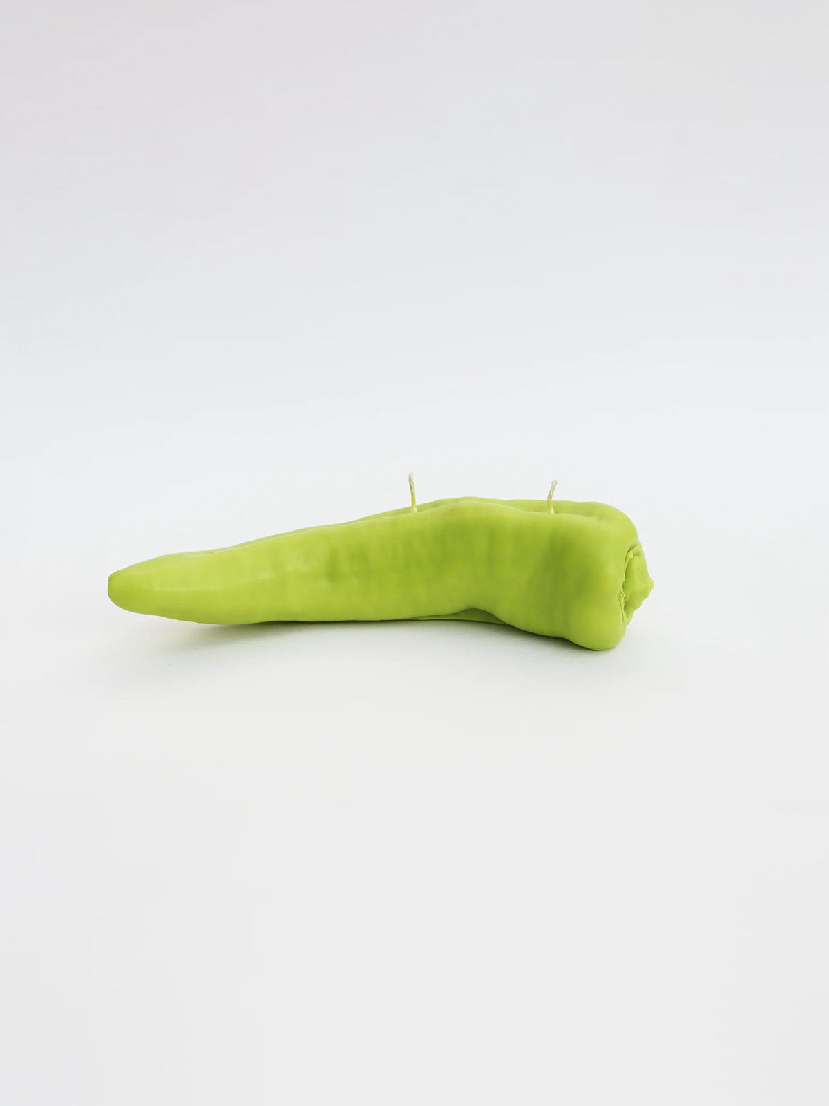 A Green Chilli Candle by Nonna&#39;s Grocer on a white surface.