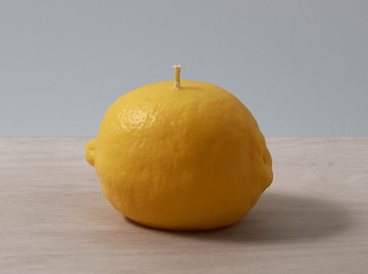 A Nonna&#39;s Grocer Lemon Candle on a wooden table.