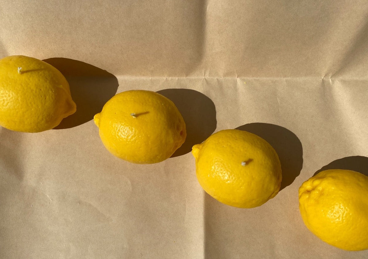 Four Nonna&#39;s Grocer Lemon Candles are lined up on a piece of paper.