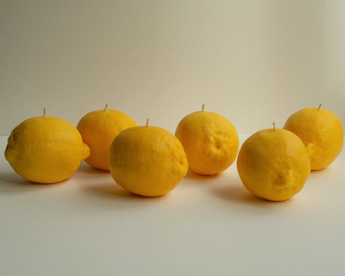 A row of Nonna&#39;s Grocer Lemon Candles on a white surface.