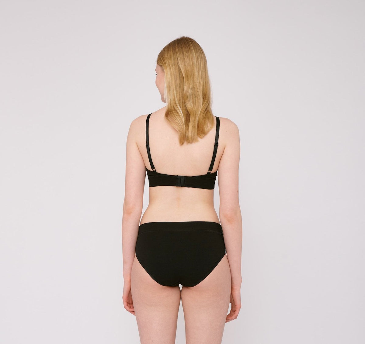 The back view of a woman wearing Organic Basics&#39; Bikini Briefs ⋅ organic cotton (2-pack) – Black.