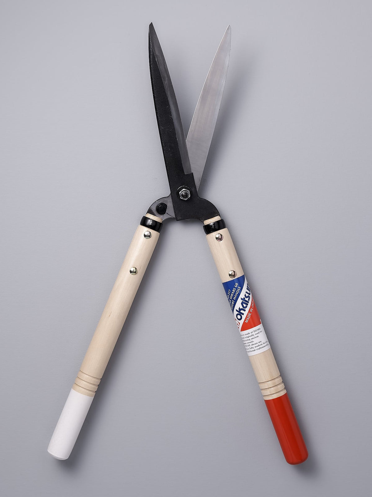 A pair of Okatsune Japanese Hedge Shears №217 – Short Handled with a red, white and blue handle.