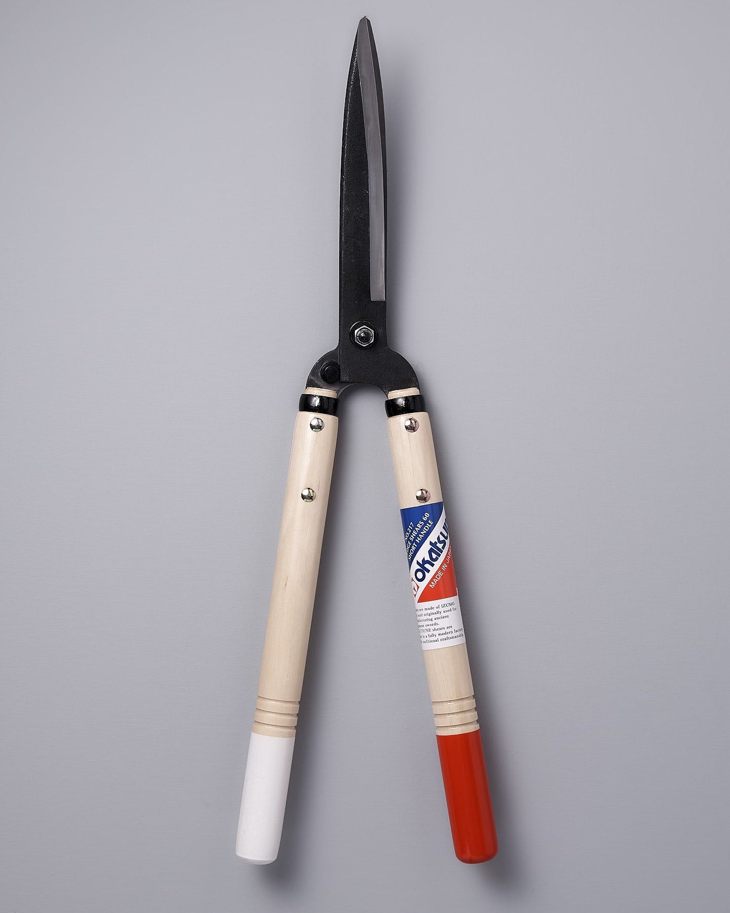 A pair of Okatsune Japanese Hedge Shears №217 – Short Handled with red and white handles.