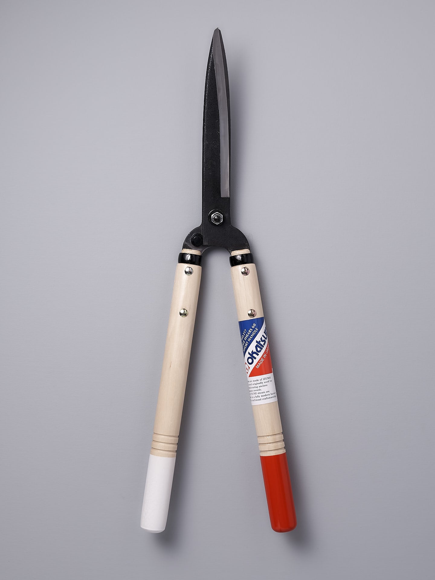 A pair of Okatsune Japanese Hedge Shears №217 – Short Handled with red and white handles.