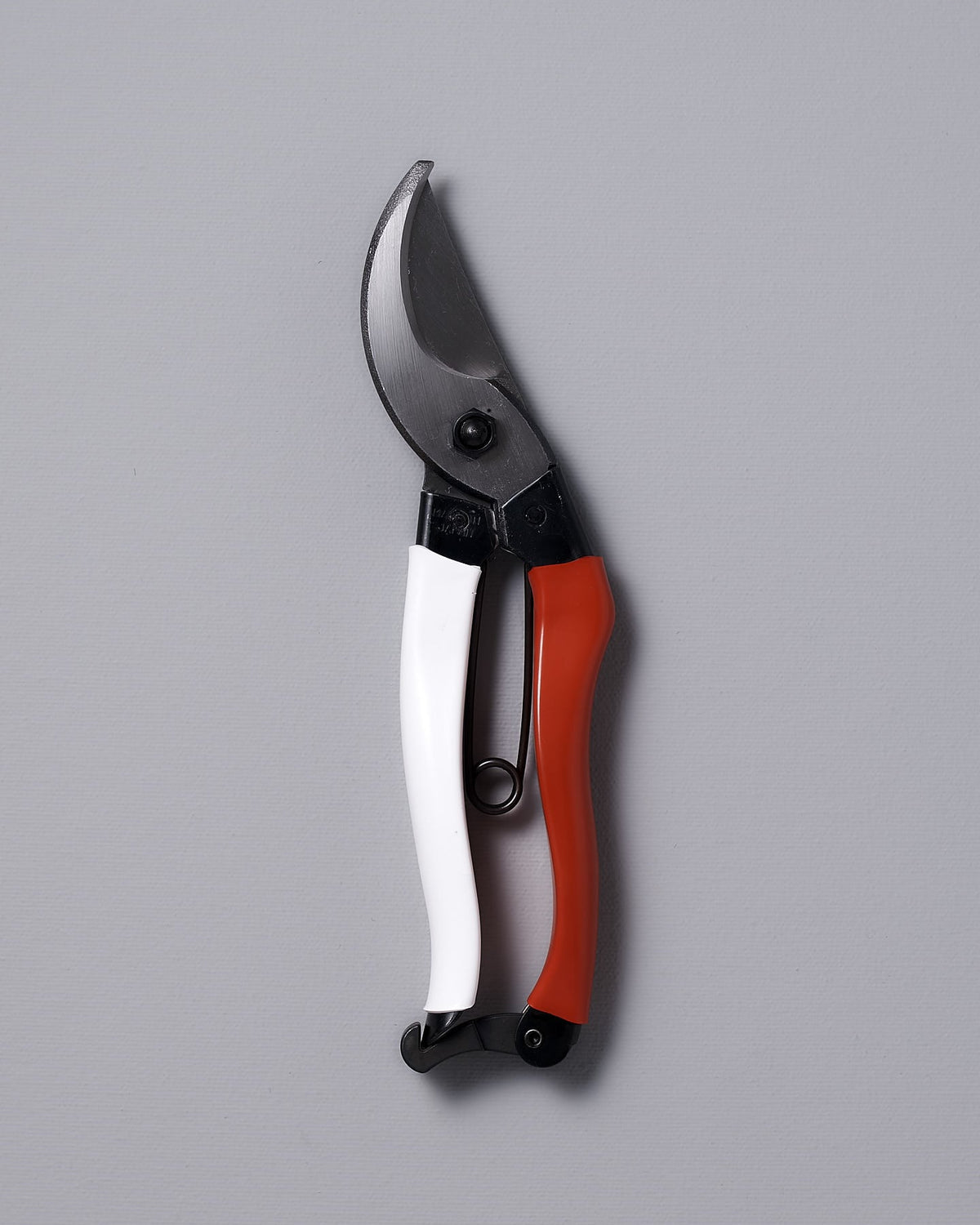 A pair of Okatsune Japanese Secateurs №103 with a white and red handle, elegantly resting on a gray background, comes bundled with a leather holster.