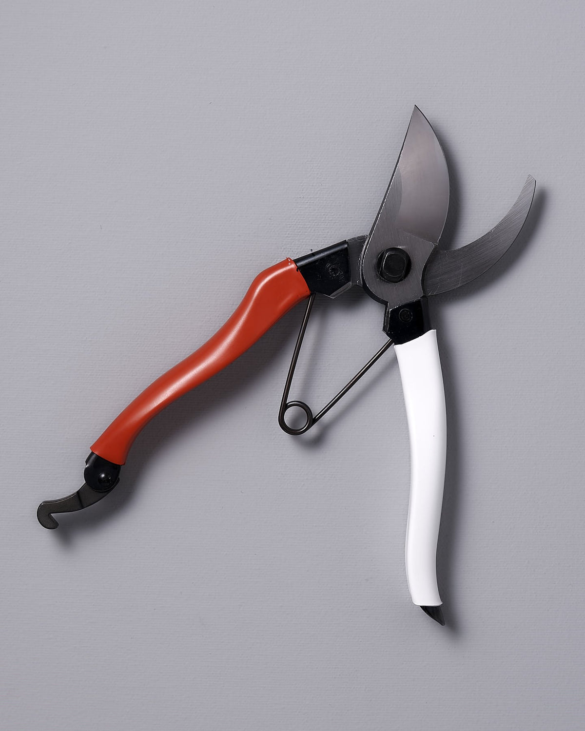 The Japanese Secateurs №103 & Leather Holster bundle by Okatsune features pruning shears with a red handle on the upper blade and a white handle on the lower blade, displayed against a gray background. Made from Japanese steel, these secateurs include an elegant leather holster for secure storage.
