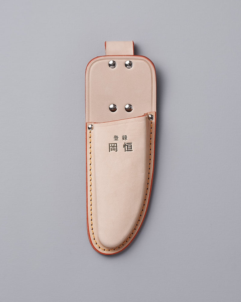 The Okatsune Japanese Secateurs №103 & Leather Holster – Bundle includes a beige leather holster adorned with metal rivets and a top loop, featuring Asian characters prominently on the front. It is expertly crafted to securely hold Japanese steel knives, all showcased against a gray backdrop.