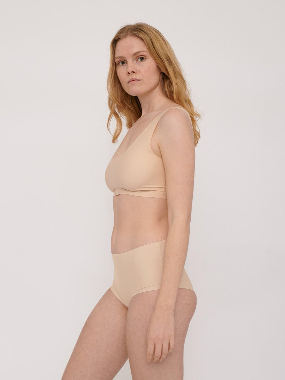 A woman wearing Organic Basics&#39; Invisible Cheeky High-Rise Briefs (2-pack) – Oak bikini top and panties.