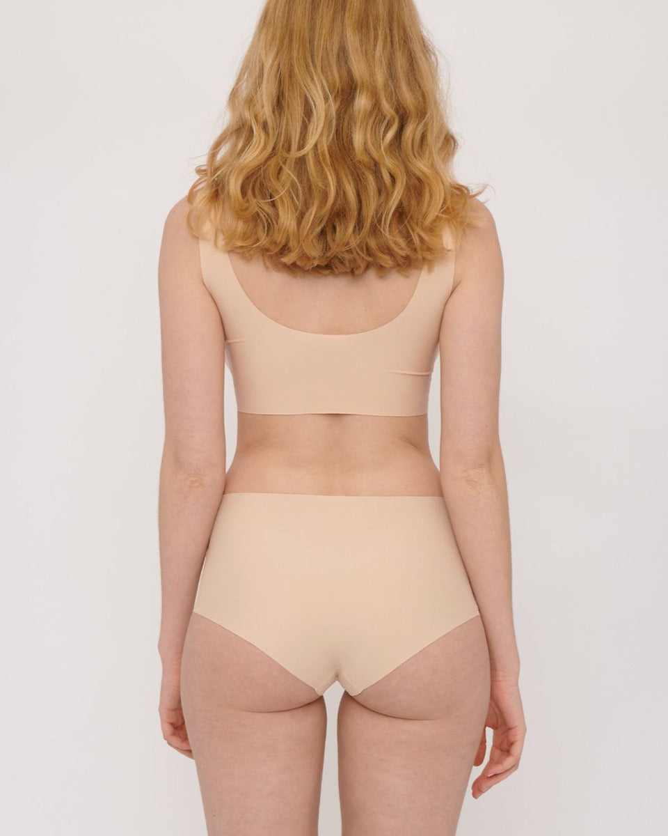 The back view of a woman in Organic Basics' Invisible Cheeky High-Rise Briefs (2-pack) – Oak bikini.