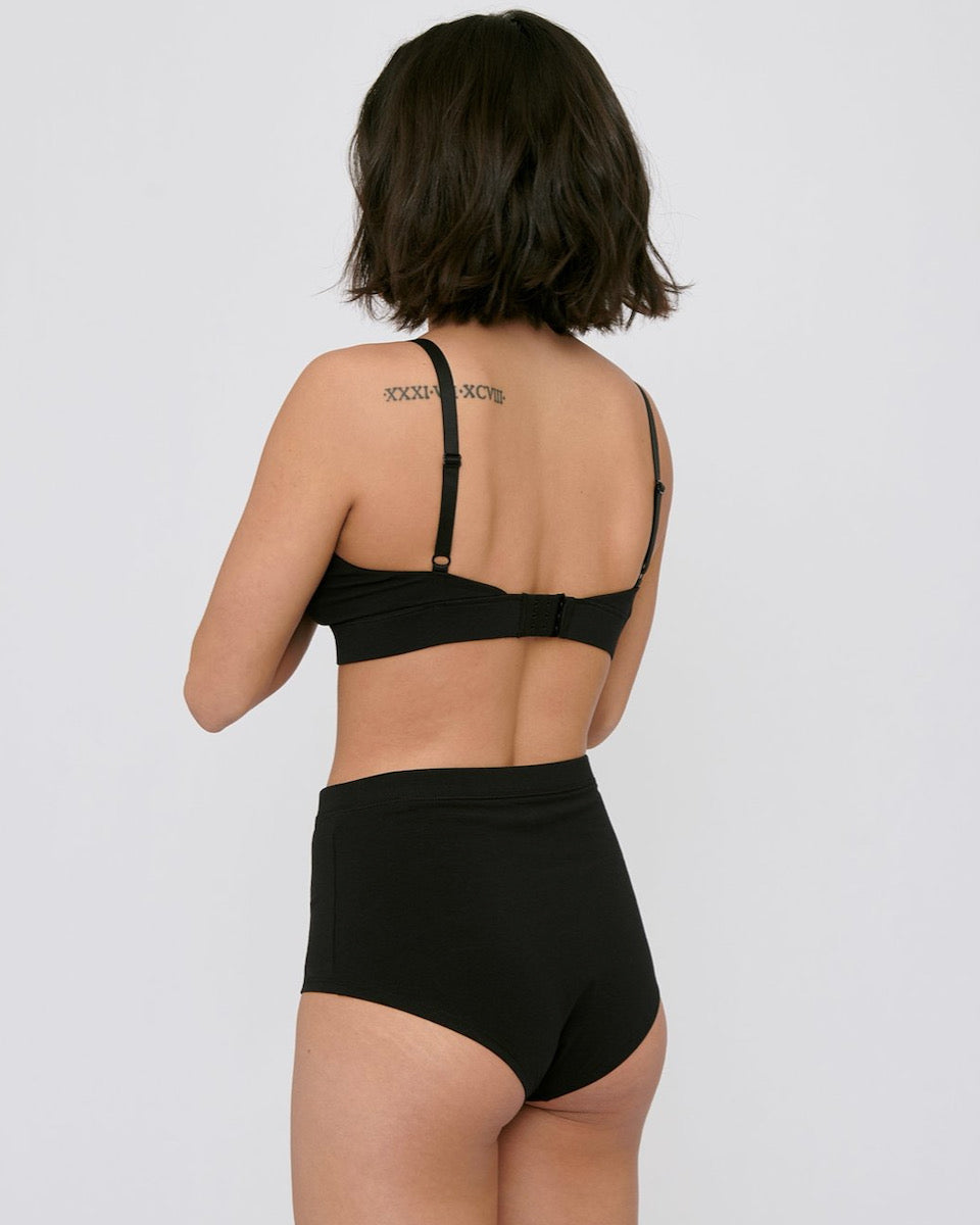 The back view of a woman wearing Organic Basics' Super High-Rise Briefs ⋅ organic cotton – (2-pack) – Black.