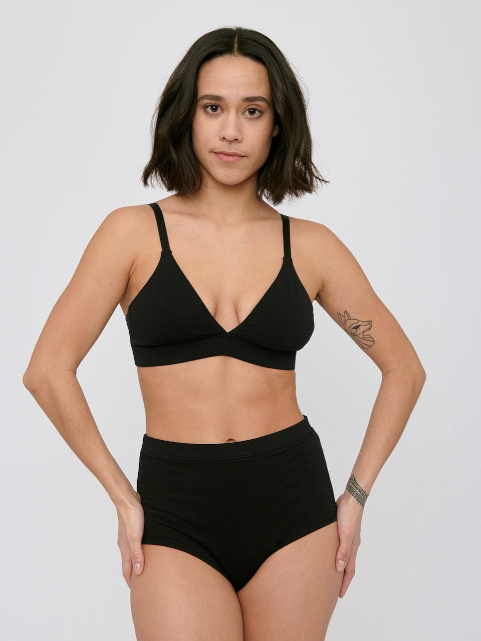 A woman wearing Organic Basics&#39; Super High-Rise Briefs ⋅ organic cotton – (2-pack) – Black bikini top.