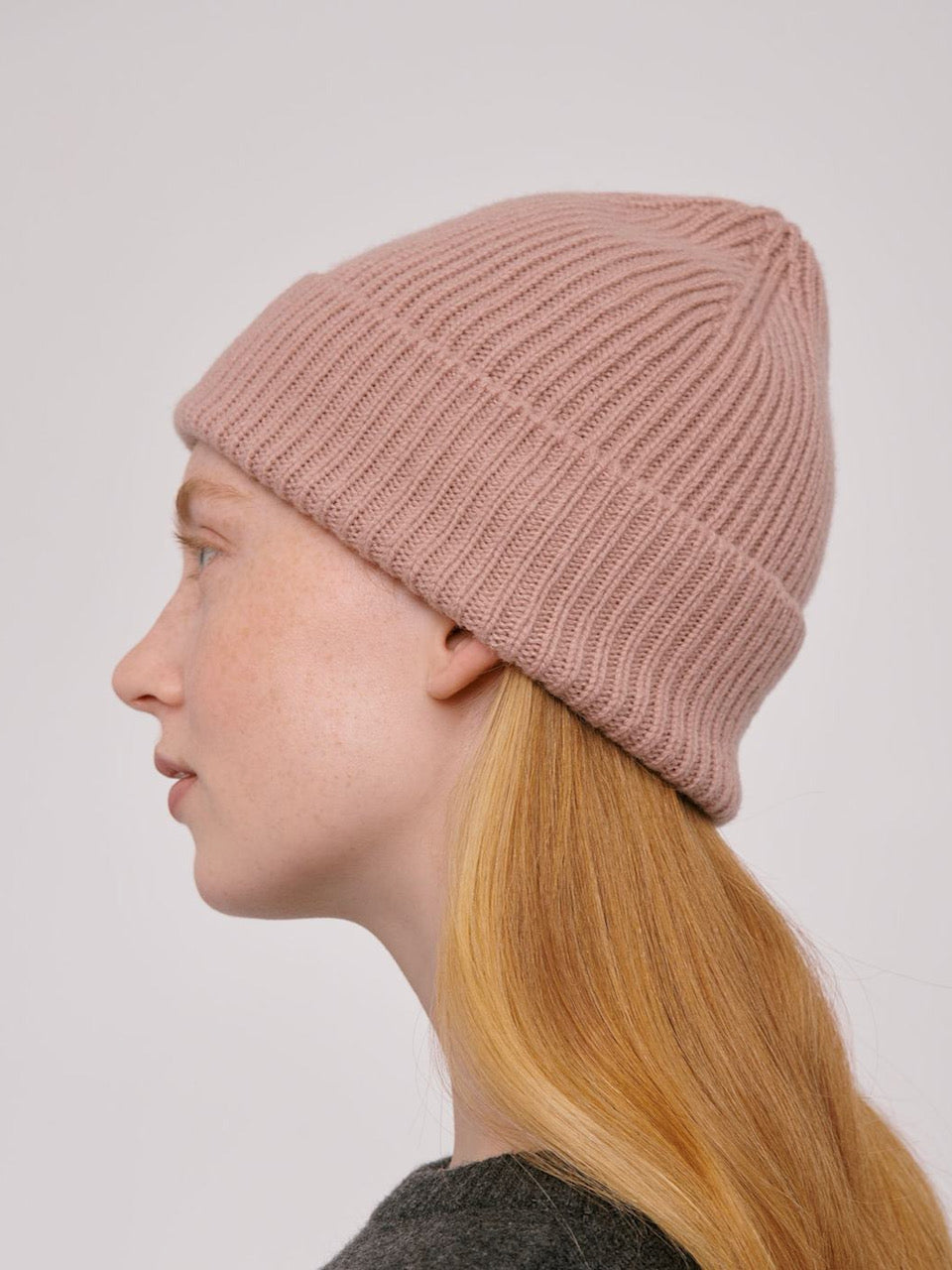 A woman wearing an Organic Basics Recycled Wool Beanie – Dusty Rose.