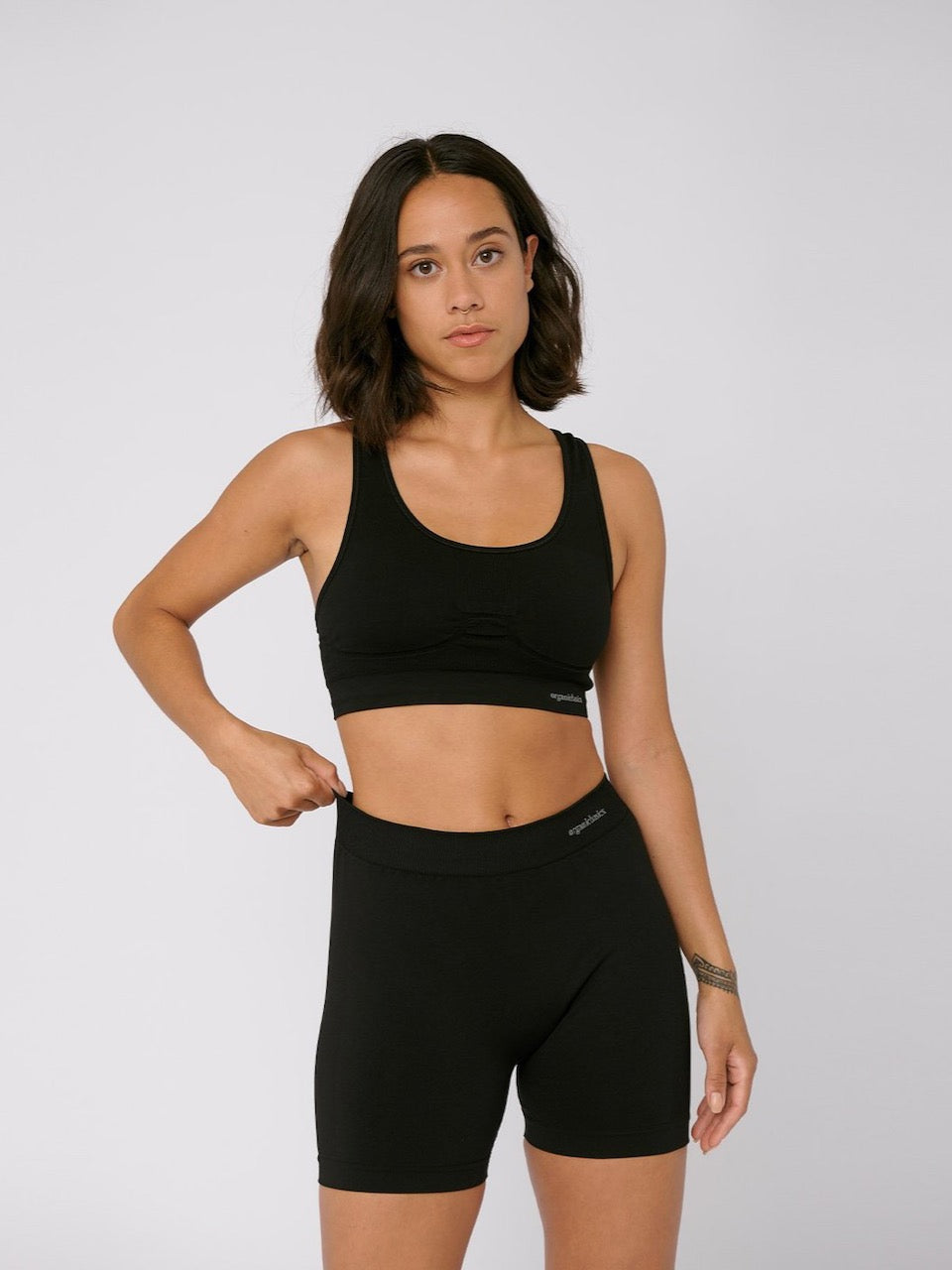 A woman wearing a Organic Basics SilverTech™ Active Workout Bra – Black and shorts.