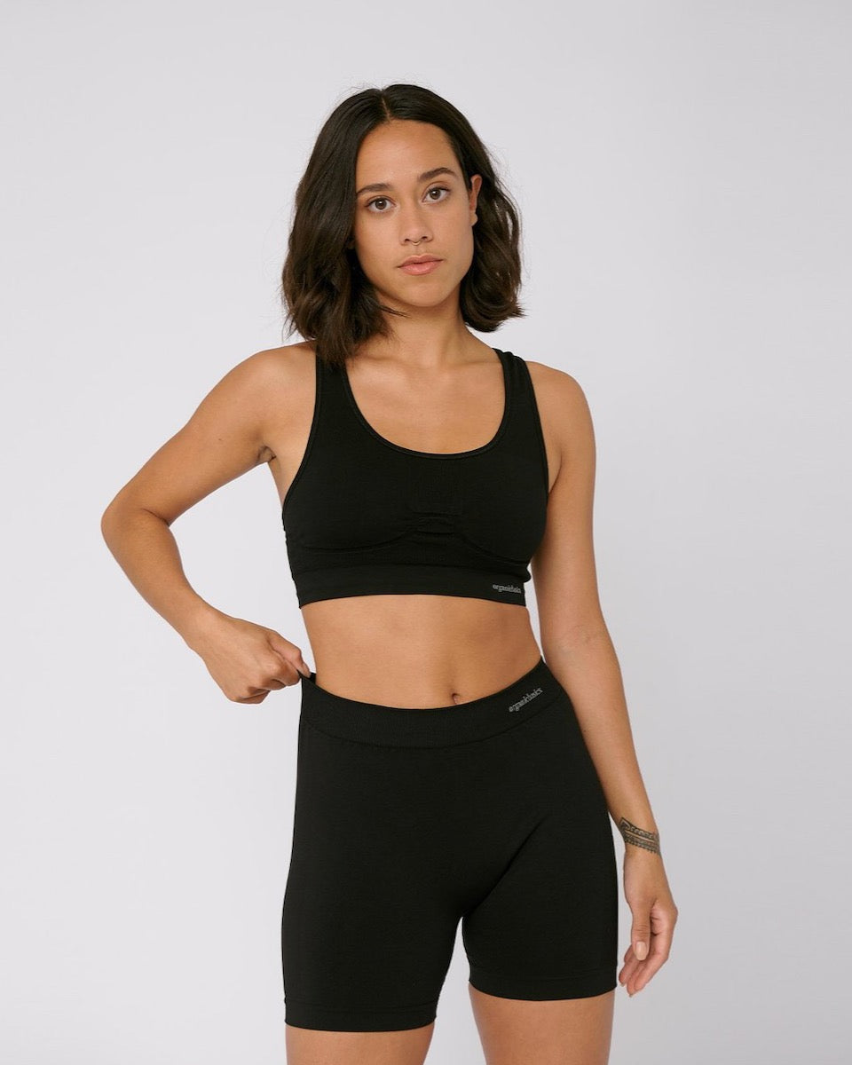 A woman wearing a Organic Basics SilverTech™ Active Workout Bra – Black and shorts.