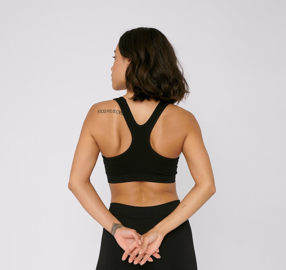 The back view of a woman wearing an Organic Basics SilverTech™ Active Workout Bra – Black and leggings.
