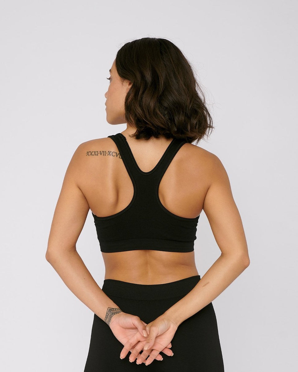 A woman wearing a Organic Basics SilverTech™ Active Workout Bra – Black and shorts.
