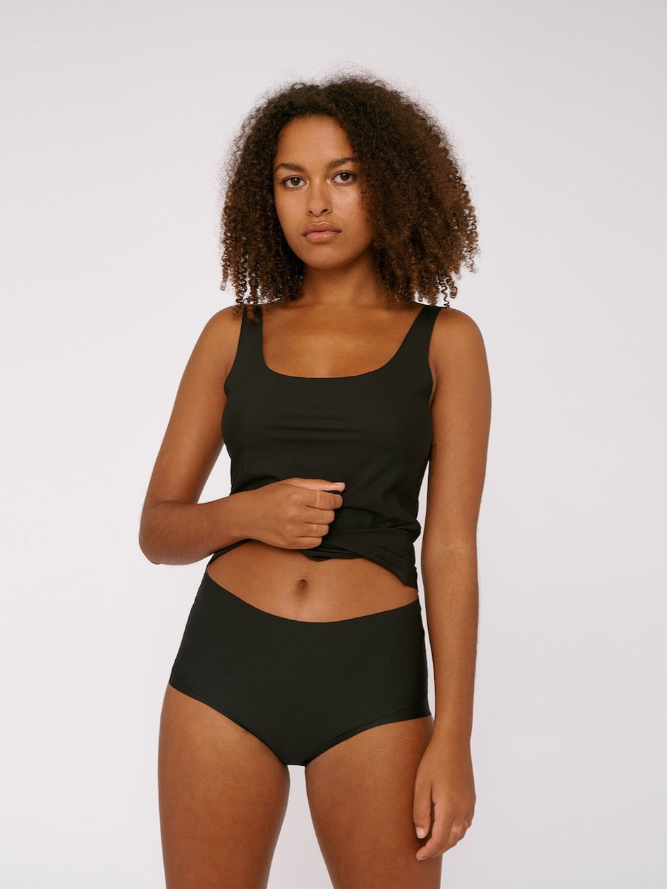 A woman wearing Organic Basics&#39; Invisible Cheeky High-Rise Briefs (2-pack) in black.
