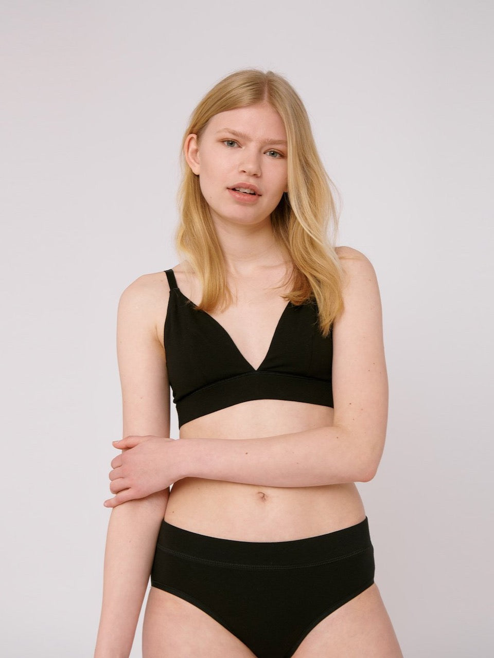 A woman wearing an Organic Basics Triangle Bra ⋅ organic cotton – Black bikini top.