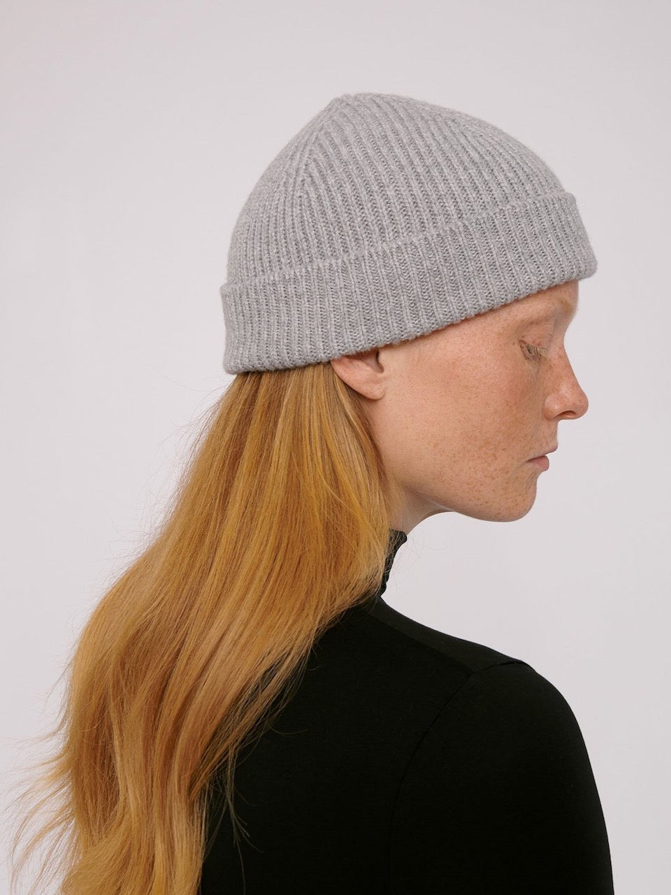A woman wearing a Recycled Cashmere Beanie – Grey by Organic Basics.
