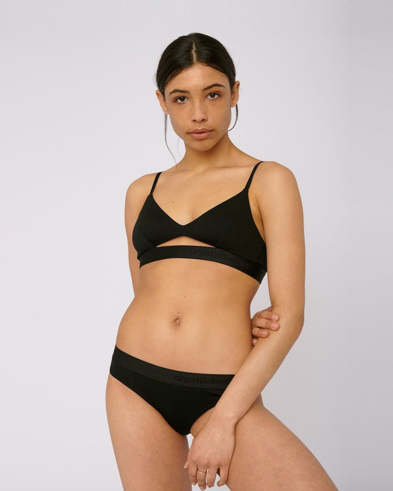 A woman wearing Organic Basics TENCEL™ Lite Briefs (2-pack) – Black bikini top and panties.