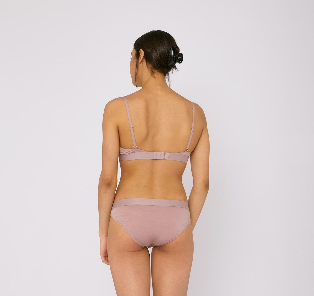 The back view of a woman wearing Organic Basics&#39; TENCEL™ Lite Briefs (2-pack) – Dusty Rose bikini.
