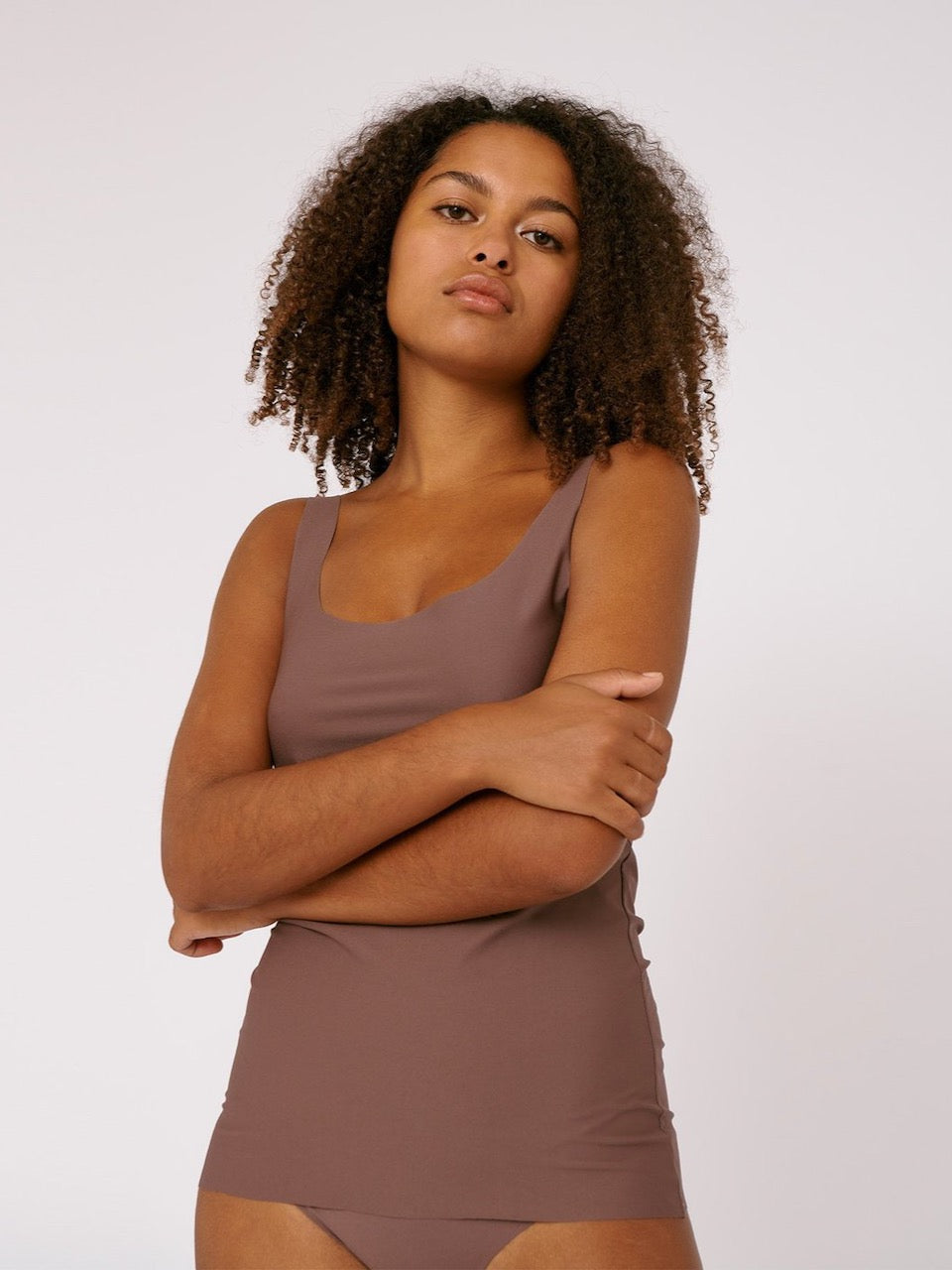 The model is wearing a Organic Basics Invisible Tank Top - Deep Taupe.