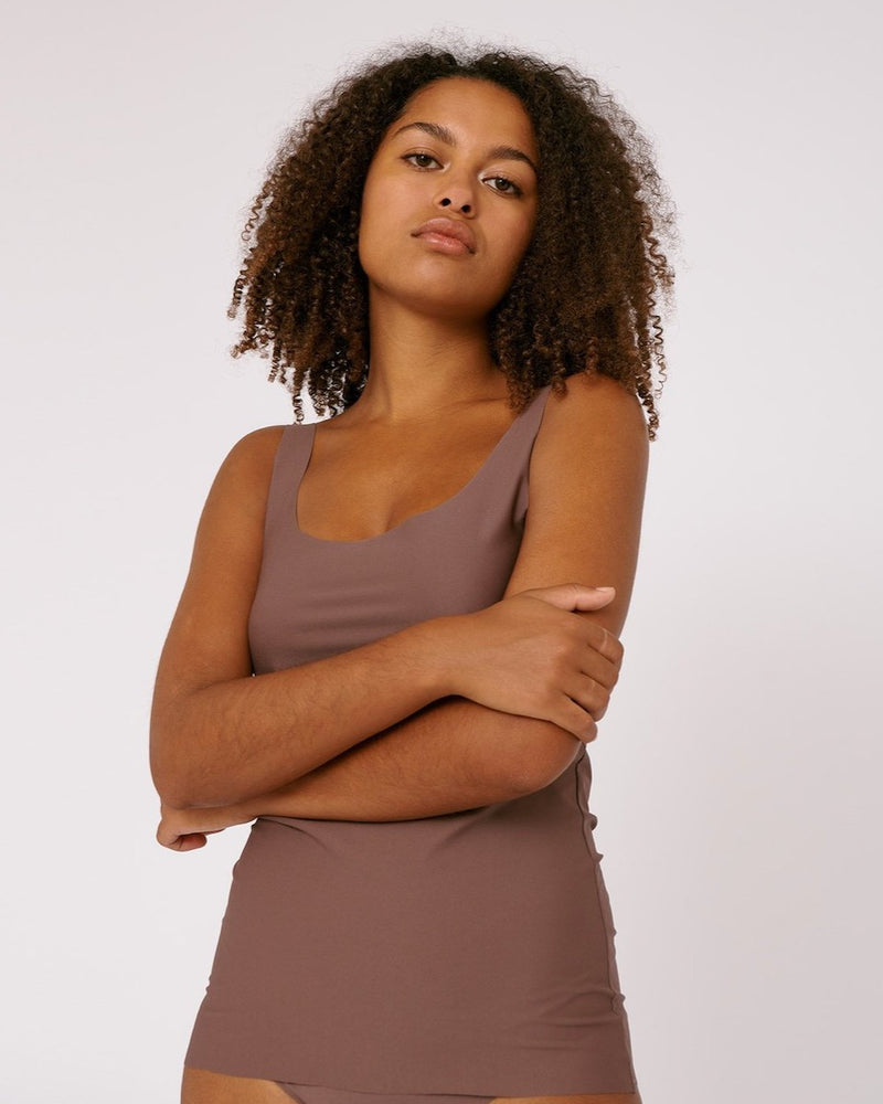 The model is wearing a Organic Basics Invisible Tank Top - Deep Taupe.